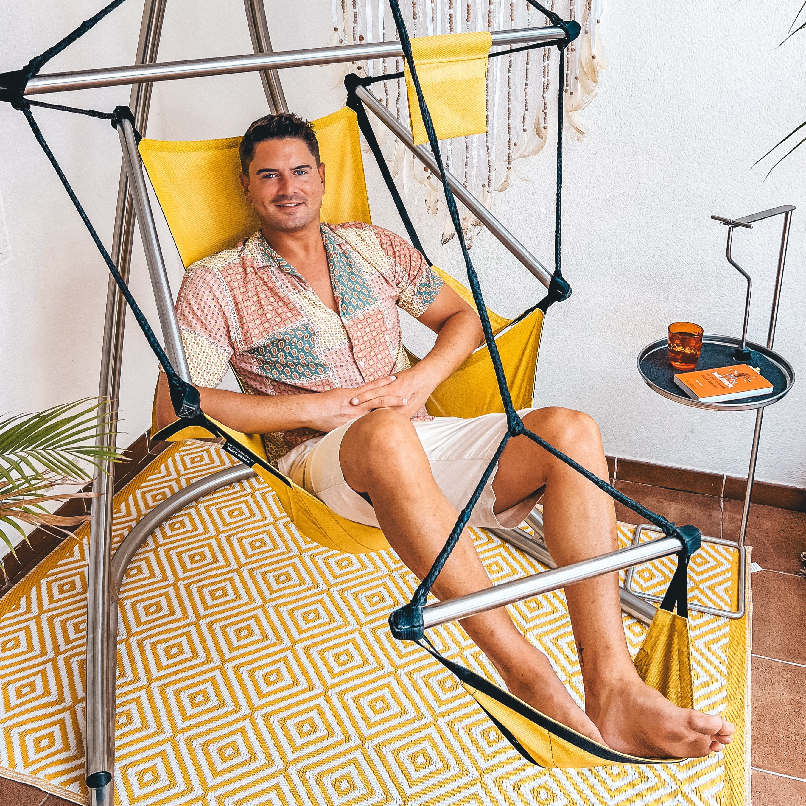 Mann entspannt im Hängesessel mit Fußstütze auf Balkon – höhenverstellbar und rückenfreundlich