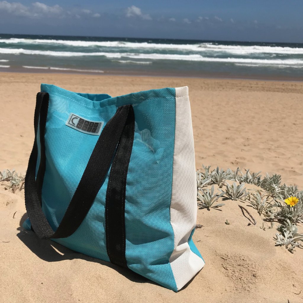 Robuste Strandtasche aus wetterfestem Gewebe in Türkis-Weiß, ideal für Urlaub, Strand und Freizeitaktivitäten.