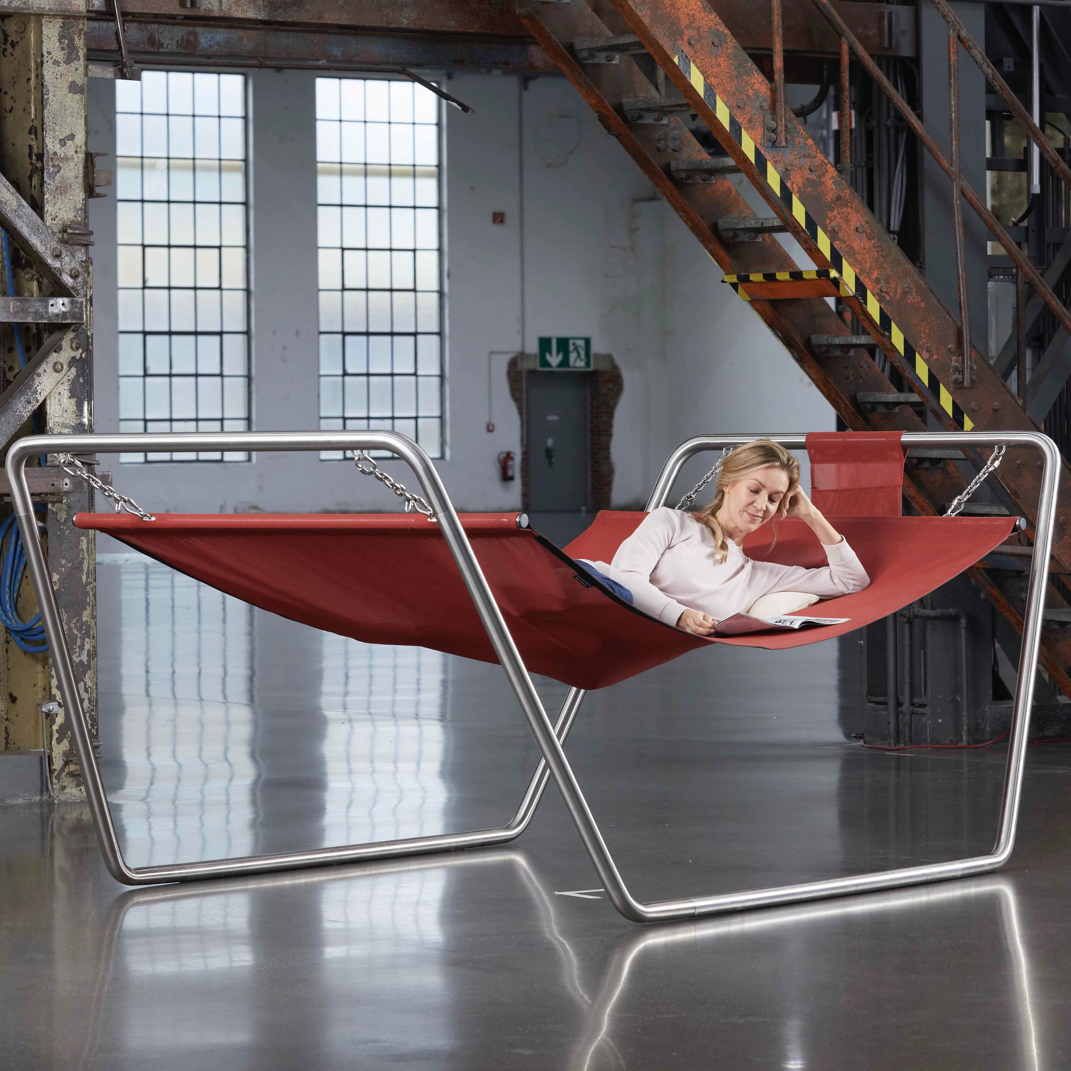 Frau entspannt im CRAZYCHAIR Daybed PONTON mit roter Liegefläche aus Batyline, montiert auf Edelstahlgestell – ideal für Garten und Terrasse.